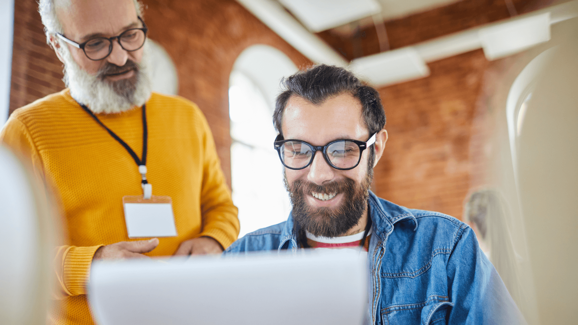 Dois profissionais analisando dados em um computador, representando a importância de medir o ROI dos benefícios corporativos para melhorar a experiência dos colaboradores