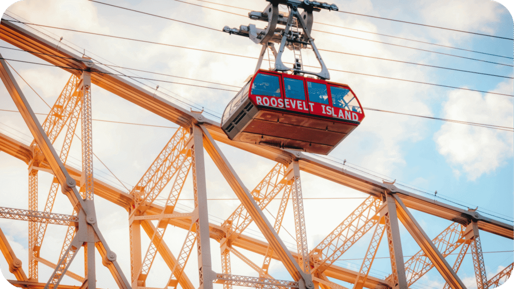 Bonde aéreo do Roosevelt Island Tramway atravessando o East River com vista para prédios de Manhattan ao fundo, em um dia claro.