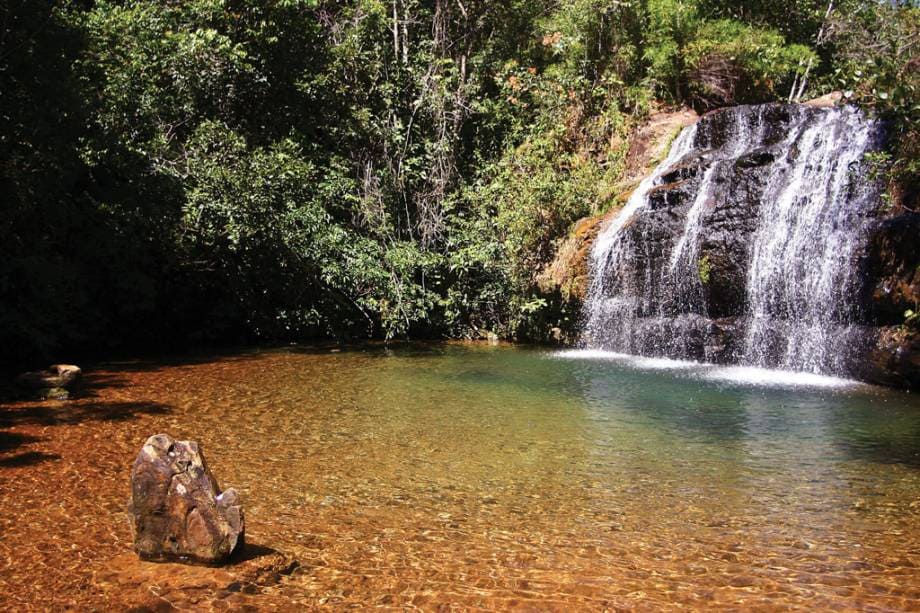 cachoeira com poço natural de águas claras em caldas novas rodeada por mata verde no outono.