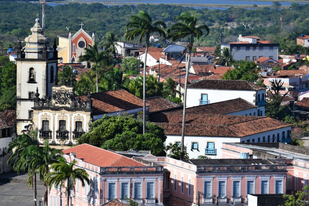 torre barroca e casarões coloniais do centro histórico de joão pessoa entre palmeiras imperiais e telhados coloniais.