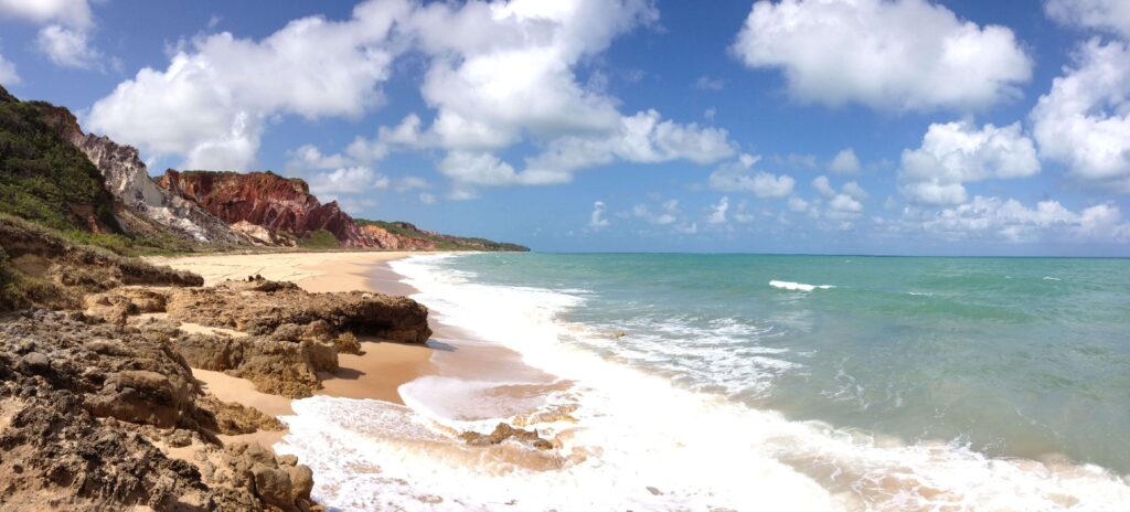 falésias coloridas e mar verde-esmeralda em uma das melhores praias de joão pessoa sob céu azul.