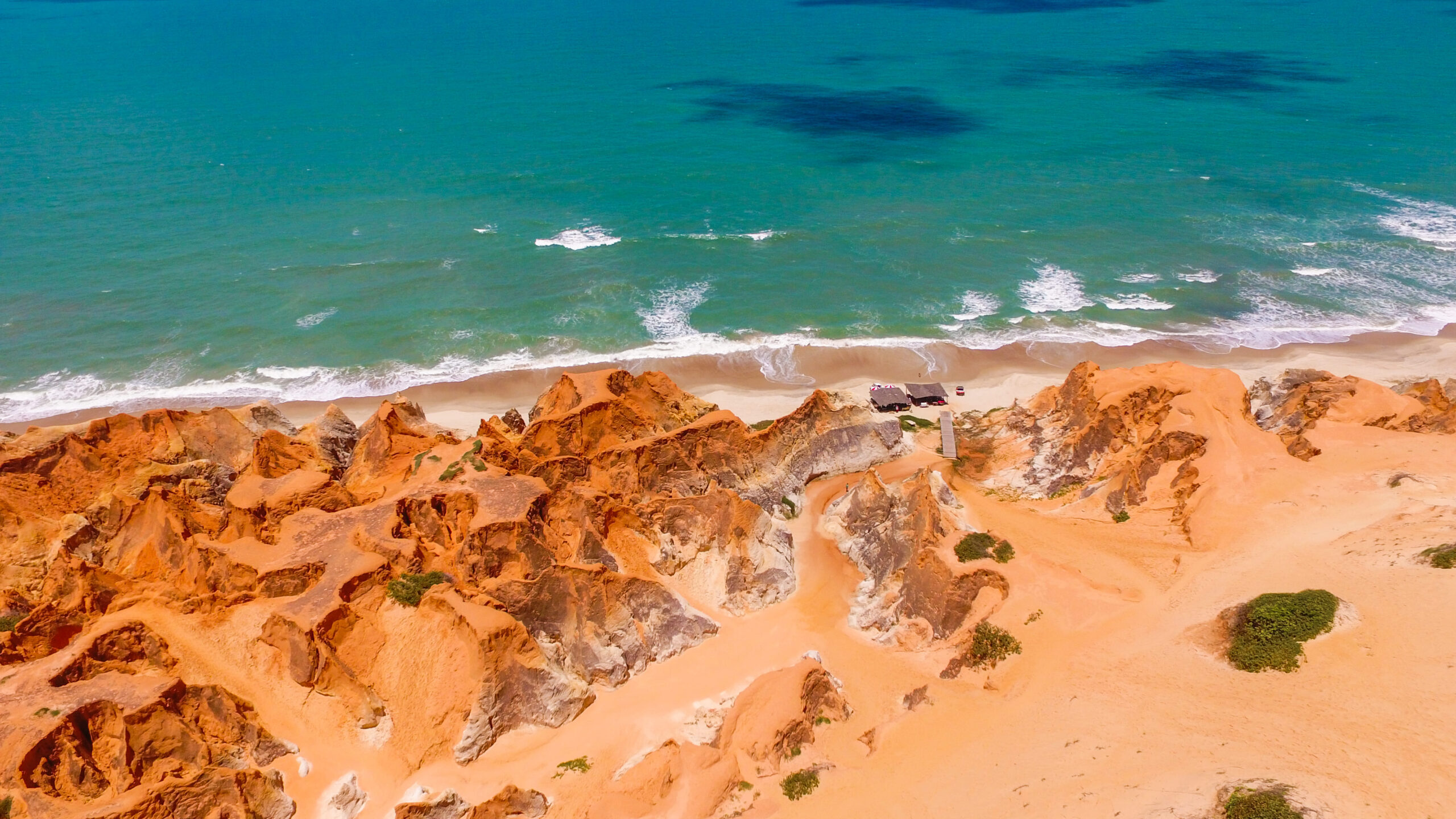 vista aérea de falésias alaranjadas com mar azul-turquesa no ceará um dos melhores destinos do nordeste em julho.