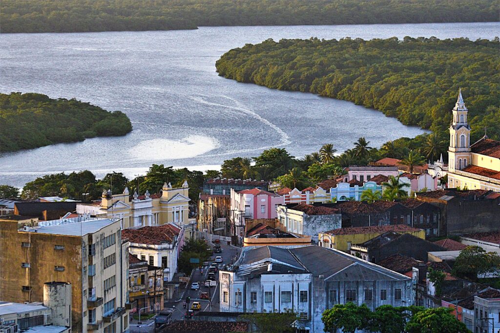 vista aérea do centro histórico de joão pessoa com casarões coloridos, rio paraíba e manguezal ao fundo.